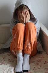 A sad, broken boy covering his face with his hands © Gosia