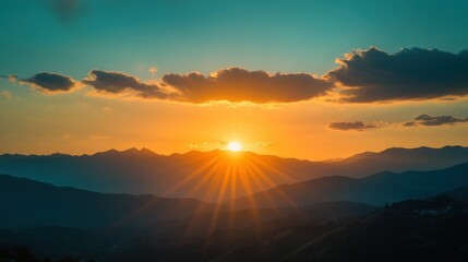 Obraz premium Sunset Over Silhouetted Mountains with Sun Rays Illuminating the Landscape