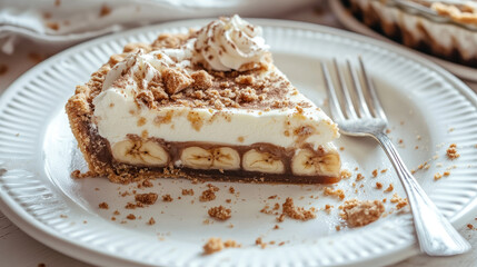 A half-eaten slice of Banoffee pie on a white plate, with crumbs scattered and a fork lying beside it, capturing the indulgence of this decadent dessert.