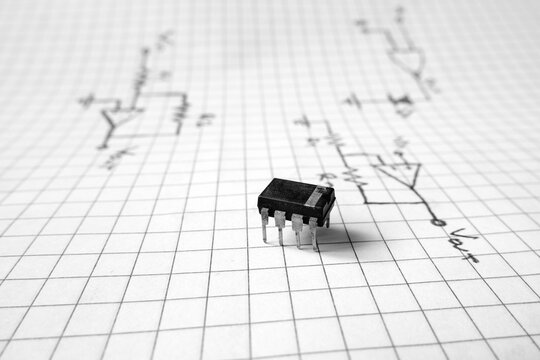 8-legged integrated circuit standing on logic circuit drawings. Industrial or technological projects concept.