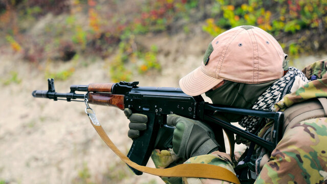 Soldier aiming with rifle during training. A soldier dressed in camouflage and tactical gear aims a rifle during a training exercise.