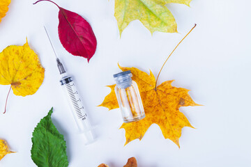 Autumn vaccination of population. Syringe in autumn leaves. Vaccination in autumn. New vaccine.