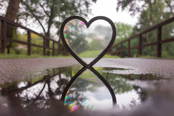 A heart shape is reflected in a puddle of water. The reflection of the heart is distorted and blurry, giving the impression of a dream or a surreal scene. Concept of wonder and mystery
