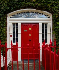 Red door with white frame and green envy around 