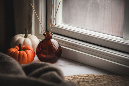 Pumpkins on the windowsill on a rainy autumn day. Perfect for creating a cozy and warm atmosphere, this image captures the essence of the season and invites tranquility and autumnal homeliness.