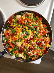 Vibrant stir-fry of colorful vegetables and rice in a pan creates a lively and delicious visual feast. 