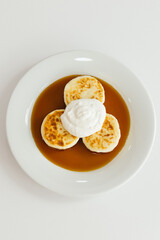 Indulge in these Delicious syrniki topped with Whipped Cream and Syrup for breakfast