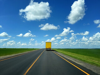 Yellow truck on the road. A vibrant yellow truck driving on an open road, symbolizing transportation and logistics.