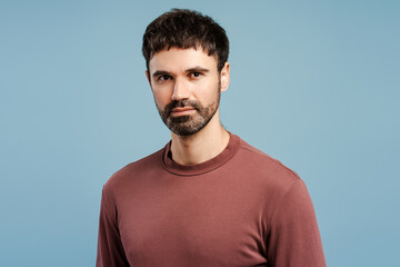 Fototapeta premium Portrait smiling bearded man wearing stylish sweater, looking at camera, isolated on blue background
