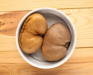 Ripe juicy kiwi in a ceramic plate on a wooden table, macro, top view.
