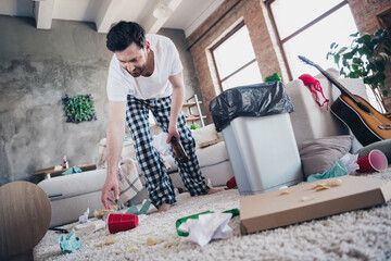 Photo of funky cool guy wear sleepwear cleaning dirty room after party indoors house apartment
