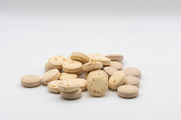 An image of a heap of round orange vitamin pills on a white background. 