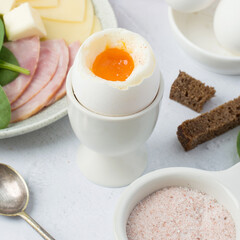 Boiled egg in a stand, pink Himalayan salt, ham, cheese, bread. Light breakfast, diet, nutrition