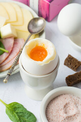 Boiled egg in a stand, pink Himalayan salt, ham, cheese, bread. Light breakfast, diet, nutrition