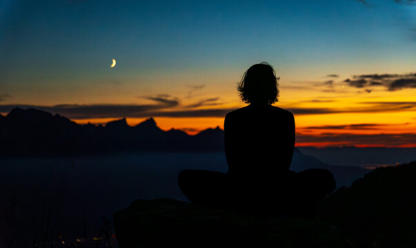 Yoga practitioner meditating in the Swiss Alps at sunset