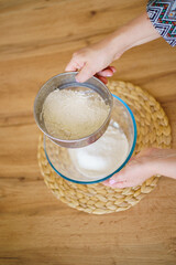 Chef preparing bread dough on a white table in his kitchen, close-up and sifting flour