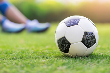 Fototapeta premium A soccer ball on grass with a player in the background during practice