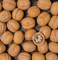 Close-up of walnuts in shells, poured on the surface in a layer. Harvest of nuts.