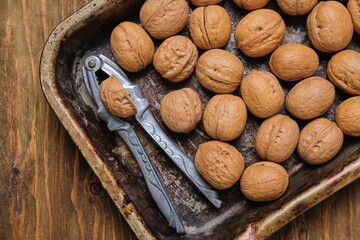 Close-up of walnuts in shells, poured on the surface in a layer. Harvest of nuts.