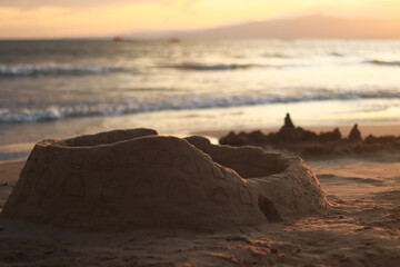 Sand castle on the beach at sunset, close-up. Sunset on the beach. Children's sand castle. Summer vacation concept. Summer background