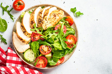 Healthy food. Green salad with grilled chicken meat at white table. Top view.