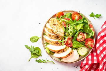 Chicken salad with grilled meat and vegetables at black table. Top view with copy space.