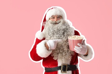 Santa Claus pointing at tasty popcorn on pink background