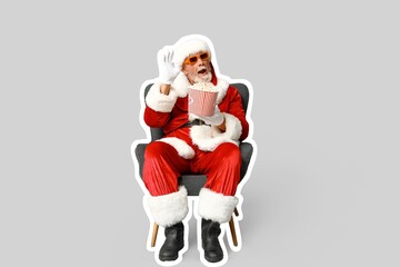 Santa Claus with 3D glasses and bucket of tasty popcorn sitting in armchair on grey background