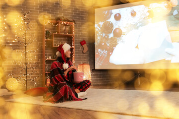 Young woman with popcorn watching Christmas movie on projector screen at home