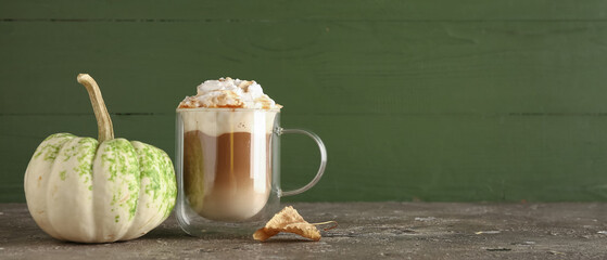 Glass cup of tasty pumpkin latte on grey table