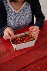 A woman is sitting at a table with a basket of strawberries in front of her