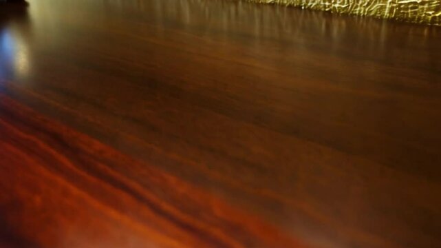 Dark wooden tabletop with a clean area for display, contrasted against a textured gold wall background.