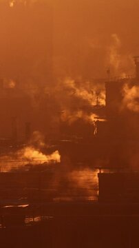 A chilly winter morning dawns, with the sun rising over the rooftops of tall buildings in Russia. The warm air rises from the vents of central heating systems