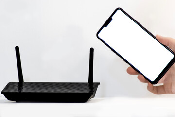 hand holding phone on the white background and router with antens