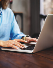 Young woman working with a laptop. Female freelancer connecting to internet via computer. Blogger or journalist writing new article.