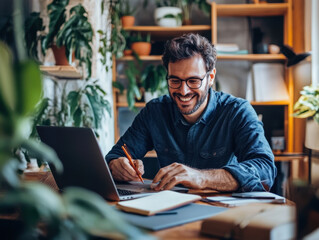 Fototapeta premium Cheerful young man working on his laptop in a bright caf? filled with greenery