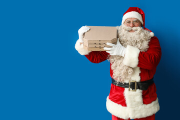 Santa Claus with pizza boxes on blue background