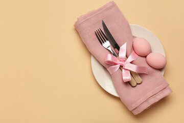 Stylish table setting with Easter eggs, napkin and cutlery on beige background