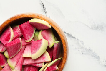 Wooden bowl with pieces of ripe watermelon radishes on white background