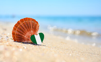 Sandy beach in Nigeria. Flag of Nigeria in the shape of a heart and a large shell. A wonderful seaside resort.