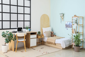Stylish interior of modern children's room with houseplants and laptop