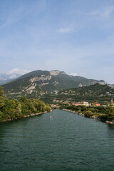 Obraz premium View of a river and a mountain in a town Linfano by Lake Garda, Italy with a person on a stand up paddling board