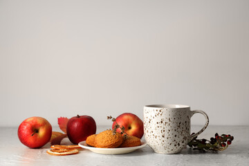 Composition with cup of green tea, apples and cookies on table near white wall