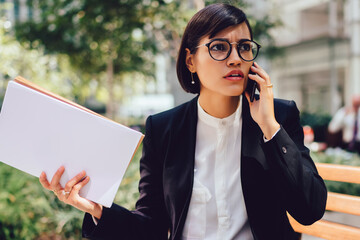 Worried female entrepreneur discussing financial news of company during mobile conversation via...