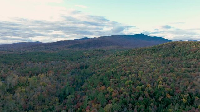 Time-lapse view of a vast forest landscape, with changing light and shadows moving across the rolling hills and distant mountains under a partly cloudy sky.