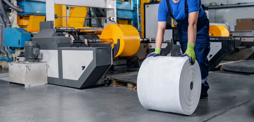 Worker installs rollers with polyethylene bags for cut. Industrial production of plastic packaging