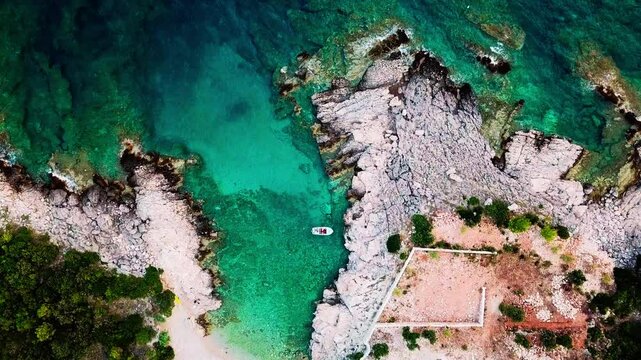 Top Down z Drona: Zacumowana Ł&oacute;dź przy Skalistej Plaży nad Morzem Adriatyckim w Słoneczny Dzień