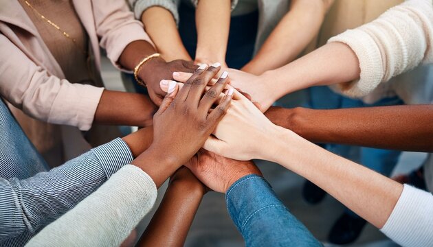 A group of people with their hands in the middle and stacked on top of each other's hands; a team huddle with all hands on deck; teamwork makes the dream work; communication photography