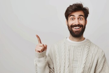 Young man in casual sweater smiling and pointing upwards.