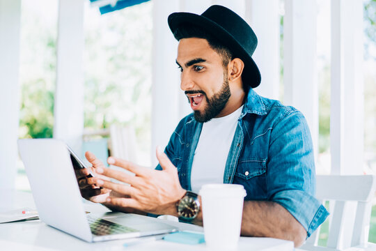 Emotional hipster guy shocked with received advertising message with promo code - discount and promotion in favourite web store, astonished man reading news in group chat from work feeling shocked